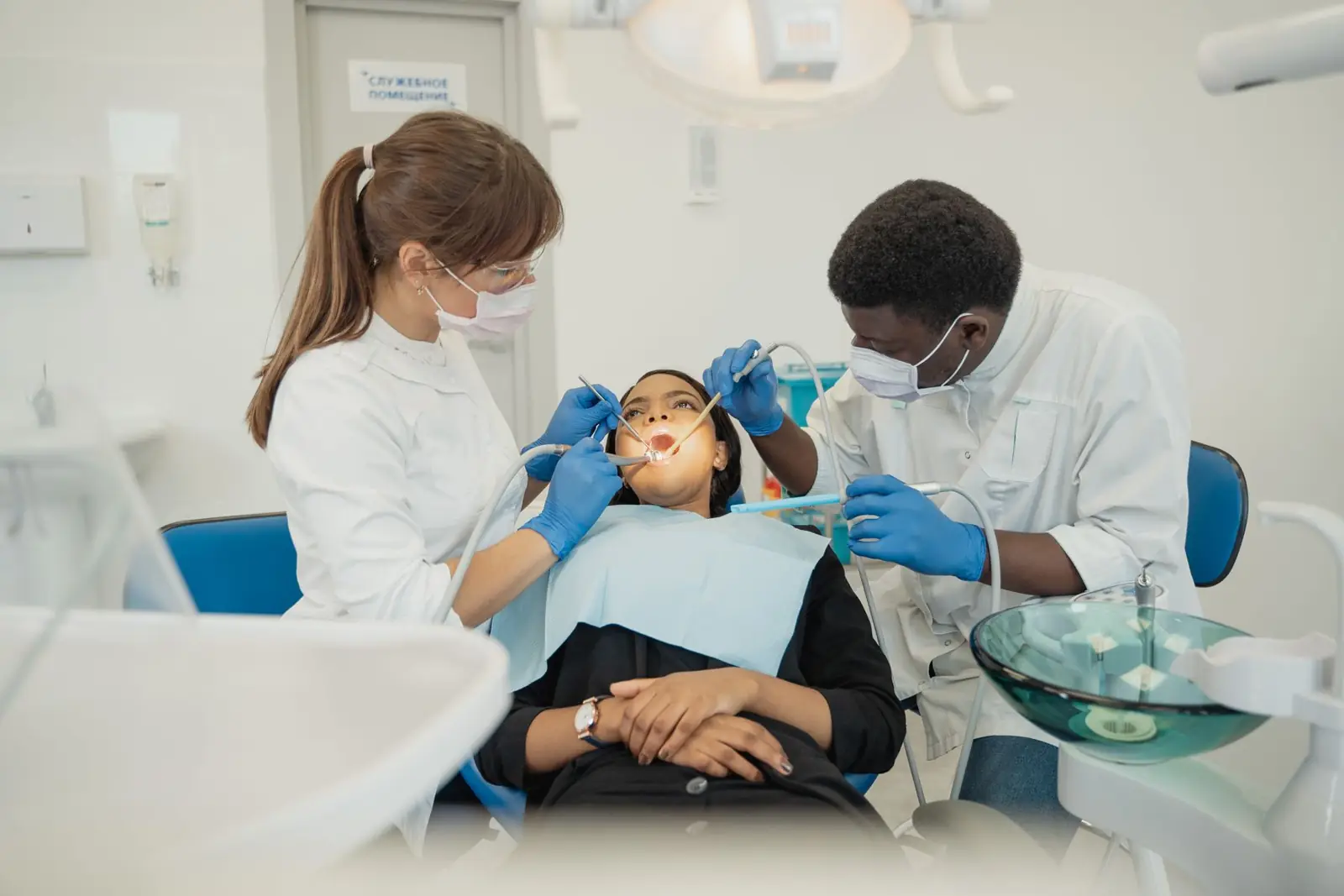 Two dental professionals treat a patient in a modern clinic setting.